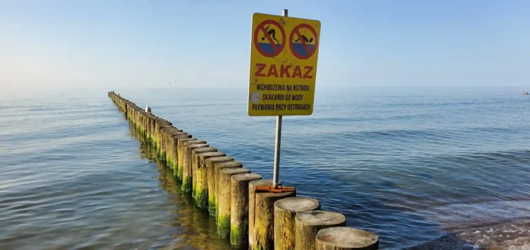 Znak ostrzegający przed ostrogami na plaży jako przykład na kontekst w bezpieczeństwie ruchu drogowego.