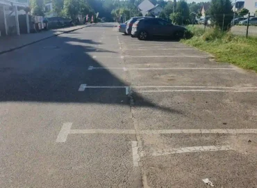 Nieprawidłowe oznakowanie poziome na parkingu - stare, grube linie i nowe, wytarte cienkie linie.
