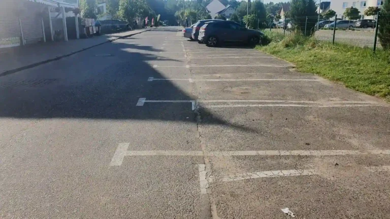 Nieprawidłowe oznakowanie poziome na parkingu - stare, grube linie i nowe, wytarte cienkie linie.