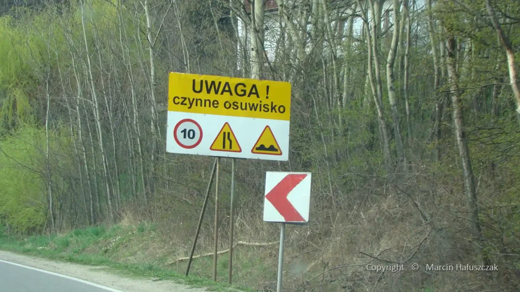 Żółty znak "UWAGA! czynne osuwisko" – przykład ryzyka klimatycznego (osuwiska) z nowego § 9 ust. 1a przepisów techniczno-budowlanych.